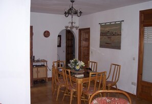 Un coin repas avec une table en bois, des chaises, un lustre et un tableau au mur.