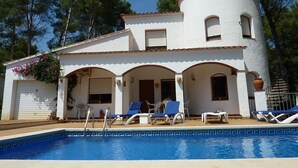 A two-story building with a swimming pool, outdoor seating, and a garage. - Villa "El Castillito" with Pool, Terrace & Wi-Fi (Playa de Pals)