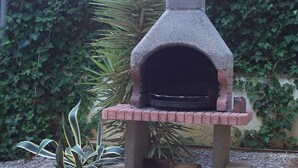 A stone-built outdoor oven with a brick base, surrounded by greenery. - Villa "El Castillito" with Pool, Terrace & Wi-Fi (Playa de Pals)