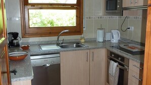 A compact kitchen with a sink, Bosch dishwasher, microwave, and wooden cabinets. - Villa "El Castillito" with Pool, Terrace & Wi-Fi (Playa de Pals)