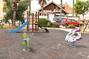 Un'area giochi con uno scivolo, una struttura per arrampicarsi e due giochi a molla.