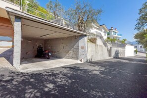 Um edifício residencial com garagem, escadaria que dá para uma varanda e céu claro.