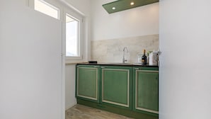 A kitchen with green cabinets, a window, and a countertop with a bottle. - Villa 'Renè' with Private Terrace, Wi-Fi and Air Conditioning (Tenno)