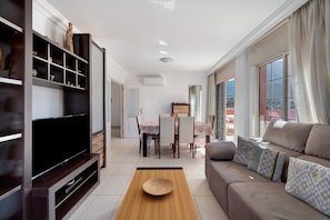 A living room with a TV, sofa, and dining area.