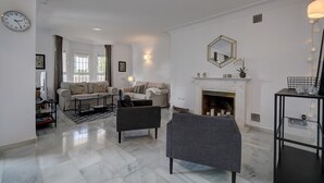 A spacious living room with a fireplace, two sofas, a coffee table, and a TV.