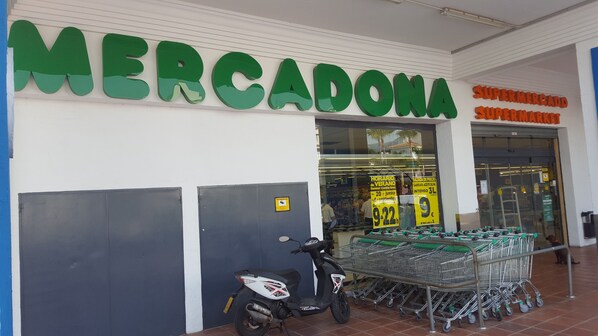 Fachada de una tienda con un gran cartel verde que dice 'MERCADONA' y 'SUPERMERCADO'.