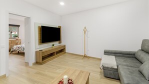 Un salon moderne avec un canapé gris, une table basse en bois et un téléviseur à écran plat fixé sur un meuble en bois.
