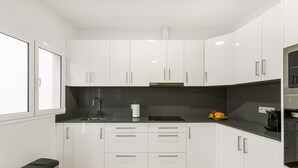 Une cuisine moderne avec des armoires blanches, un comptoir noir et une hotte de cuisinière en acier inoxydable.