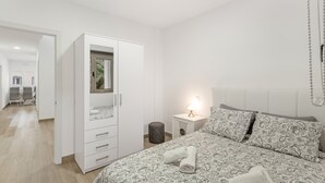Une chambre à coucher comprenant un lit, une armoire, une table de chevet avec une lampe et un miroir.