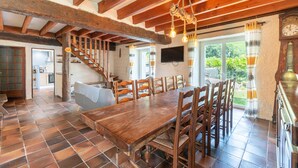 Ein Essbereich mit Holztisch und Stühlen, einer Treppe, einem Fernseher und einer Uhr.