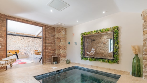 A modern interior with a swimming pool, stone walls, and a view into another room. - Apartment 'La Bergerie' with Shared Pool, Wi-Fi and Air Conditioning (Esparron)