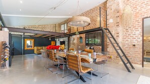 A spacious dining area with a brick wall, a wooden table, and modern chairs. - Apartment 'La Bergerie' with Shared Pool, Wi-Fi and Air Conditioning (Esparron)