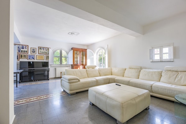 A spacious living room with a large L-shaped sofa, a glass coffee table, and a television.