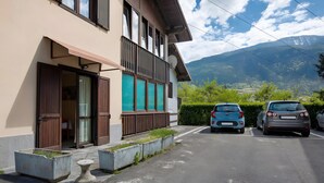 Ein Gebäude mit Balkon, einer Garage mit zwei Autos und Blick auf Berge.