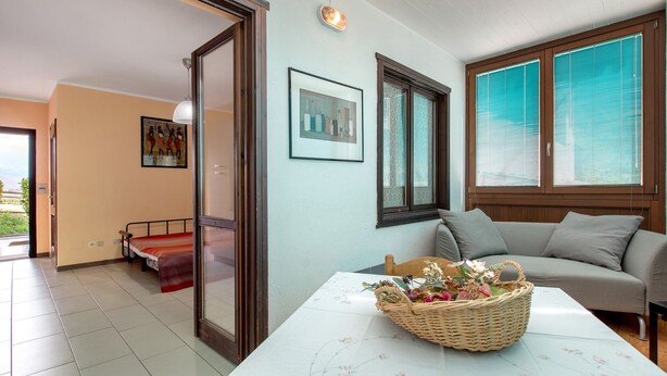 Ein Zimmer mit einem Bett, einer Couch, einem Tisch mit einem Korb und einem Fenster mit Jalousien.