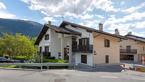 Ein zweistöckiges Gebäude mit Balkon, Garage und Bergblick.