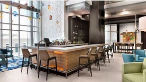 A modern bar area with a long counter, bar stools, and a view of the city through large windows. - Charming 2-bedroom beachfront resort near water parks and golf (Myrtle Beach)