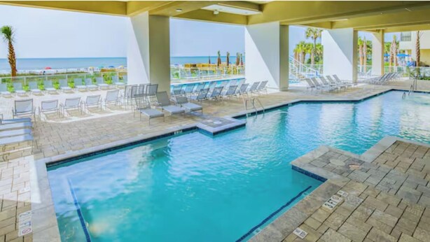 A pool area with lounge chairs and a view of the beach. - Charming 2-bedroom beachfront resort near water parks and golf (Myrtle Beach)