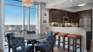 A modern kitchen with dark cabinets, a stainless steel refrigerator, and a large window offering a city view. - Charming 2-bedroom beachfront resort near water parks and golf (Myrtle Beach)