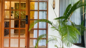 A traditional wooden door with glass panels, a potted plant, and patterned floor tiles. - Roys Villa Havelock Sky 1 (AN)