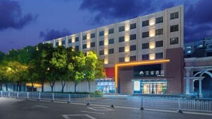 Un hotel moderno con una entrada destacada, varios pisos y una fachada bien iluminada.