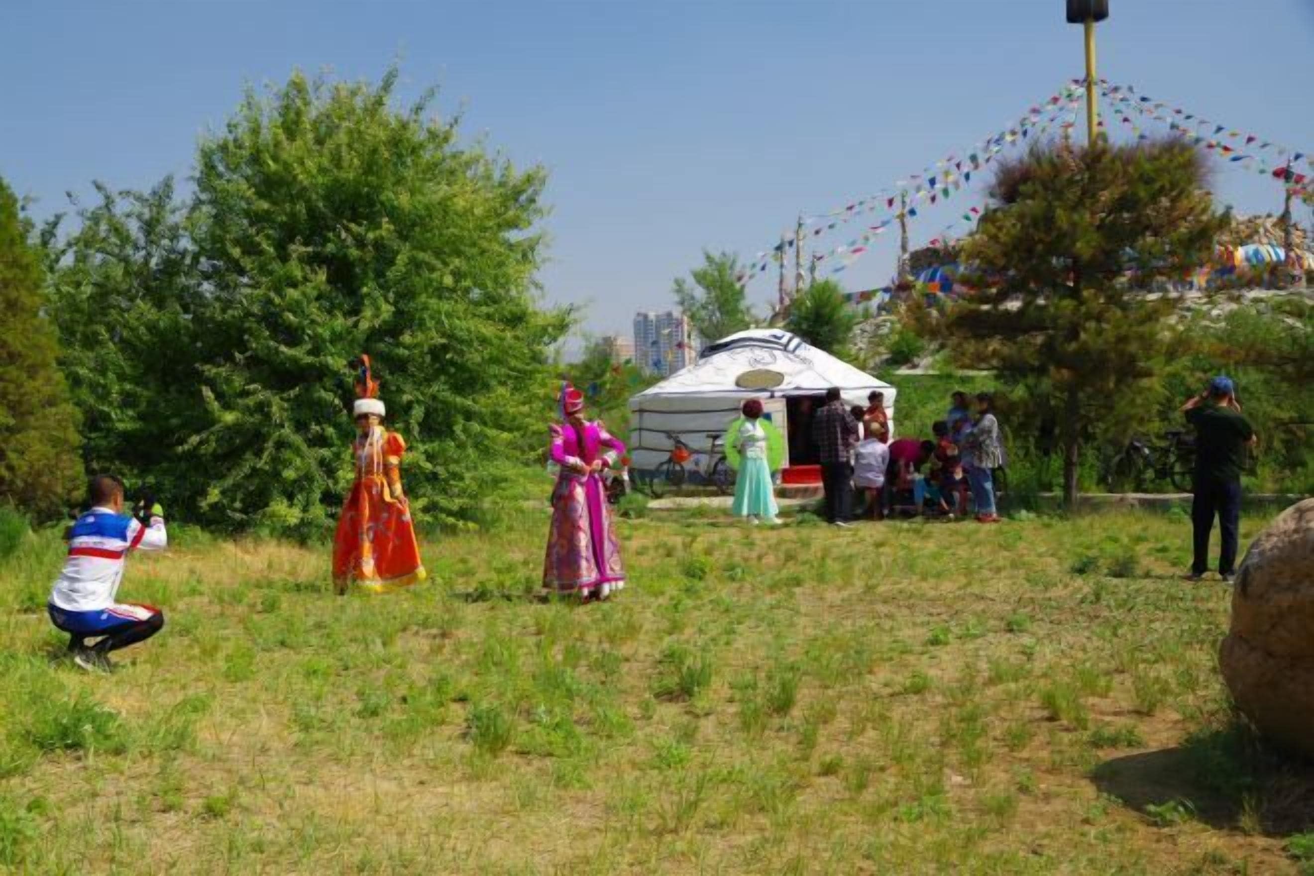 Un grupo de personas vestidas con atuendo tradicional en un entorno al aire libre, con una tienda de campaña y árboles.