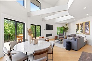 A spacious living area with a round table, sofas, and a TV mounted on the wall.