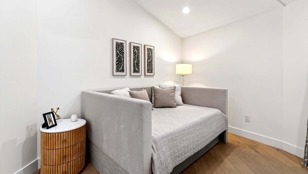 Ein Schlafzimmer mit Bett, Nachttisch, Lampe und Wandbild.