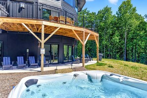 A modern building with a wooden deck, outdoor seating, and a hot tub.