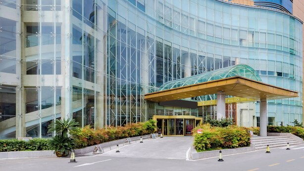 A modern glass building with a curved facade and a covered entrance. - wanxibinguan (Anqing)