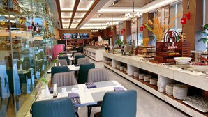A modern restaurant with glass partitions, blue upholstered chairs, and a buffet counter with various food items. - wanxibinguan (Anqing)