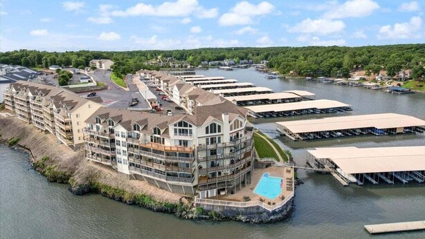 A waterfront hotel with multiple balconies, a swimming pool, and docked boats. - Lakeview Condo w/ 2 Pools & Beach - Family Fun Awaits at 21MM (Osage Beach)