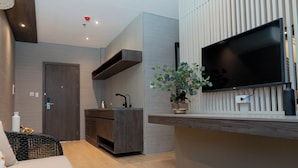 Una sala de estar moderna con televisión de pantalla plana, cocina integrada y una zona de estar acogedora.
