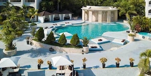 Zwembadgedeelte van een resort met meerdere zwembaden, ligbedden en parasols.