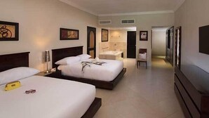 A hotel room with two beds, a TV, a bathroom, and artwork on the walls. - Presidential Suites by Lifestyles  (Puerto Plata)