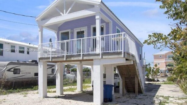 A two-story house with a balcony, a covered porch, and a small deck. - Coastal Comfort in Marathon FL2BR Poolside Retreat (Marathon)