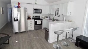 A modern kitchen with white cabinets, stainless steel appliances, and a central island with bar stools. - Coastal Comfort in Marathon FL2BR Poolside Retreat (Marathon)