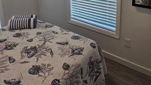 A bedroom with a bed, a TV mounted on the wall, a window with blinds, and a mirror on the wall. - Coastal Comfort in Marathon FL2BR Poolside Retreat (Marathon)