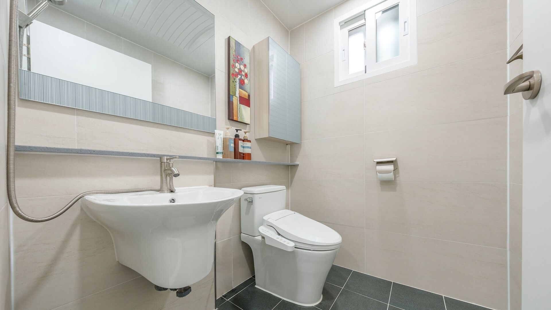 A bathroom with a white sink, a toilet, a mirror, and a shower.