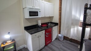 Une cuisine de taille réduite avec des meubles blancs, un lave-vaisselle rouge et un plan de travail noir.