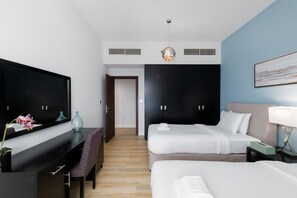 A modern hotel room with a flat-screen TV, a desk with a vase, two beds, a bench, and a large wardrobe. - Chic JBR 2BR w/ Pool and Gym, Marina Views (Dubai)