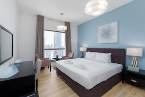 A modern hotel room with a large bed, a desk with a mirror, a chair, and a view of the city through large windows. - Chic JBR 2BR w/ Pool and Gym, Marina Views (Dubai)