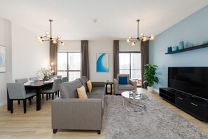 A modern living room with a sofa, dining table, and TV. - Chic JBR 2BR w/ Pool and Gym, Marina Views (Dubai)
