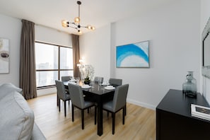 A modern dining area with a black table set for four, grey chairs, and a chandelier.