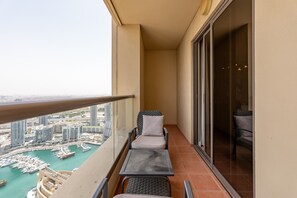 A balcony with two chairs and a table, overlooking a marina with boats and buildings.