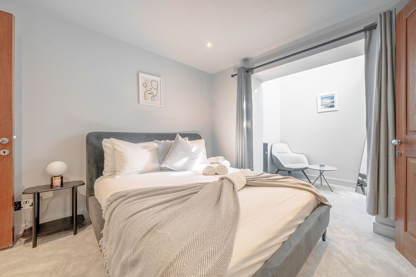 Camera d'hotel moderna con un letto grande, un tavolino, una sedia e vista sull'esterno.