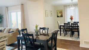 A dining area with a marble table, black chairs, and a vase of flowers.