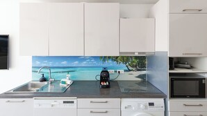 A modern kitchen with white cabinets, a built-in microwave, and a coffee machine.