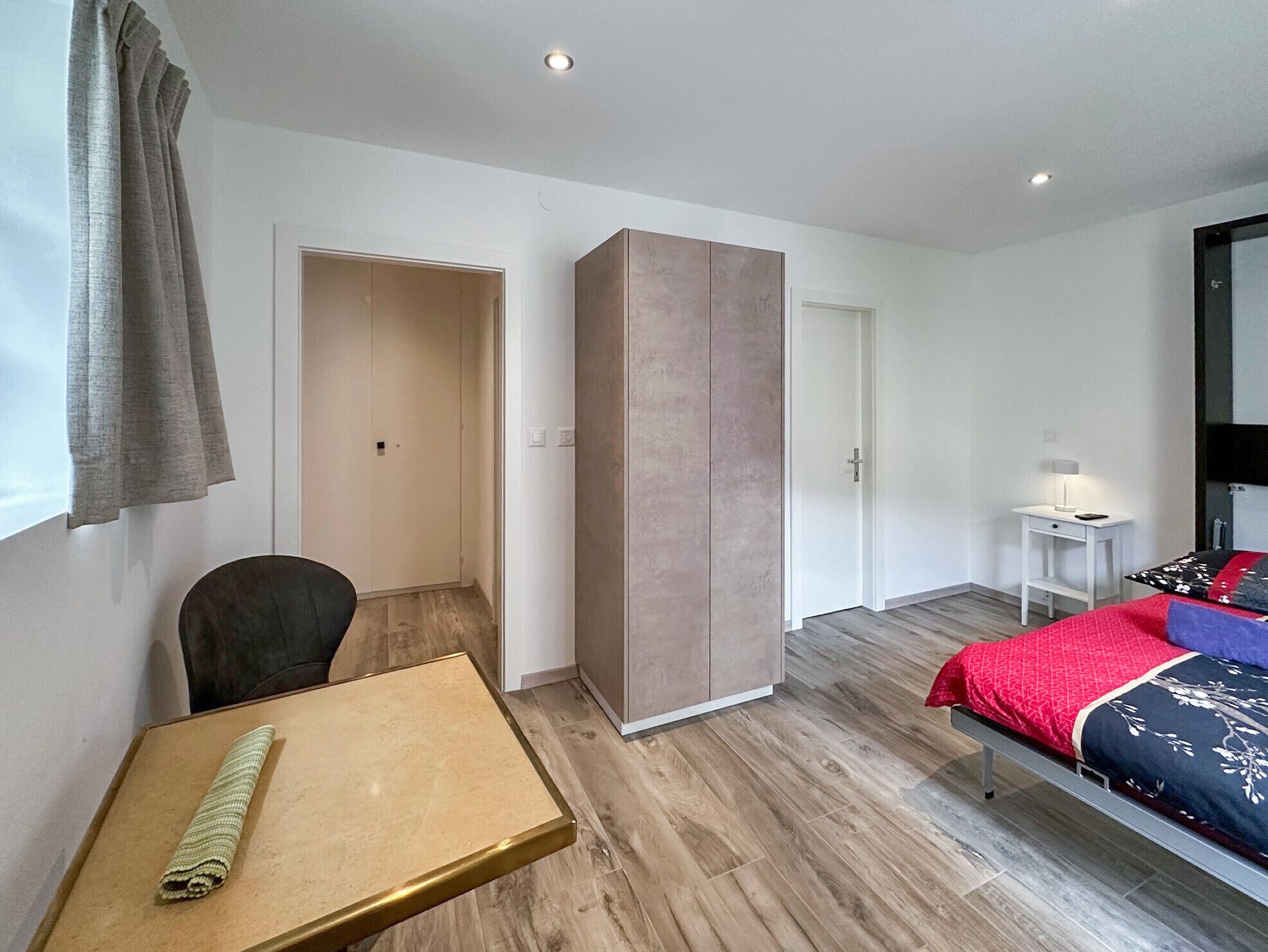 Un dormitorio moderno con cama, escritorio, armario y una silla.