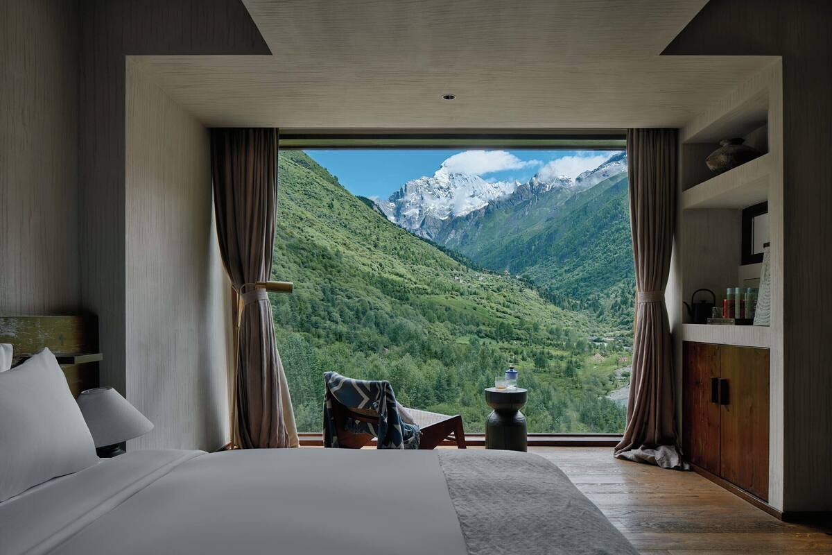 A bedroom with a large window offering a mountain view.